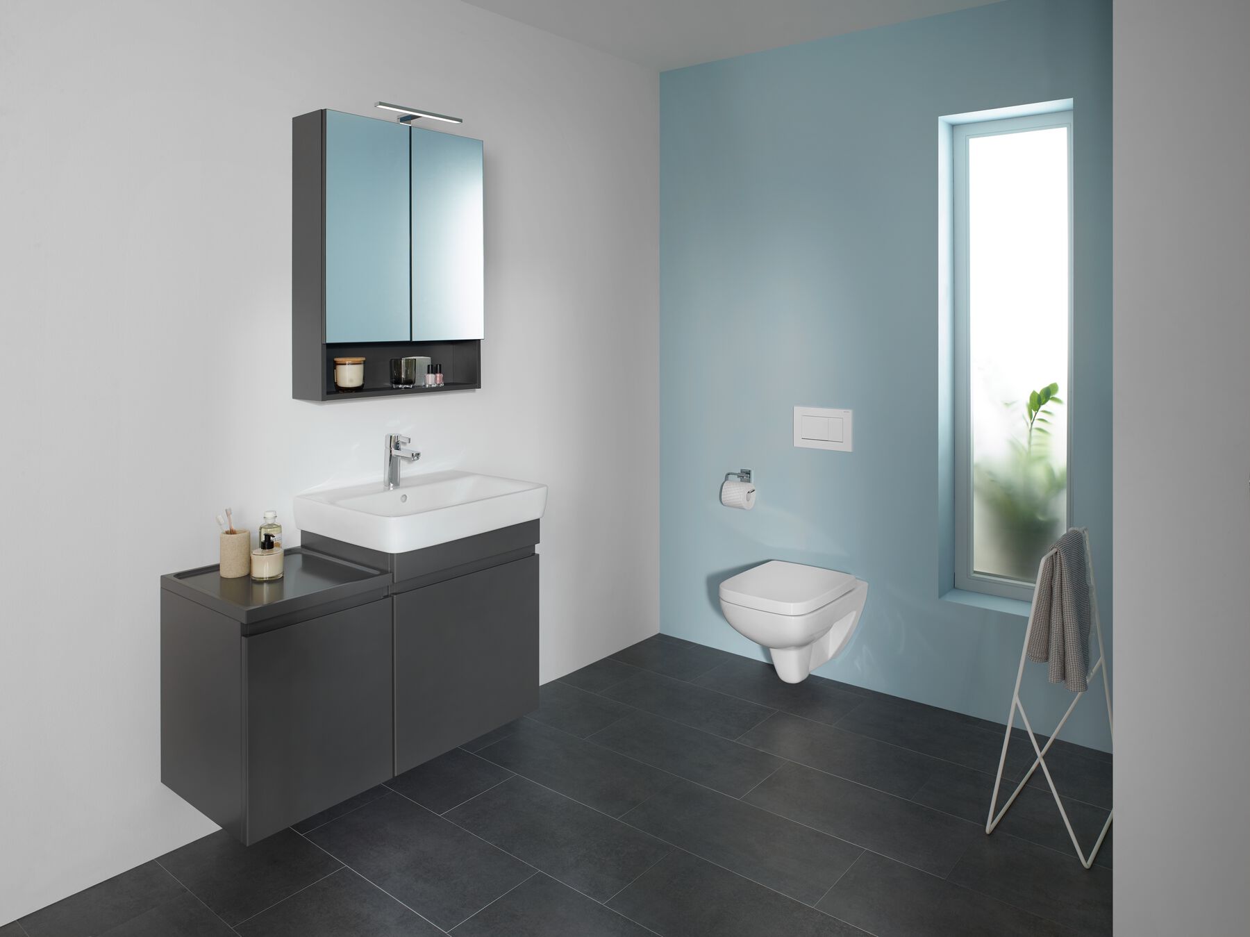 Modernes Badezimmer mit blauer Akzentwand, grauen Möbeln und weißer Einrichtung