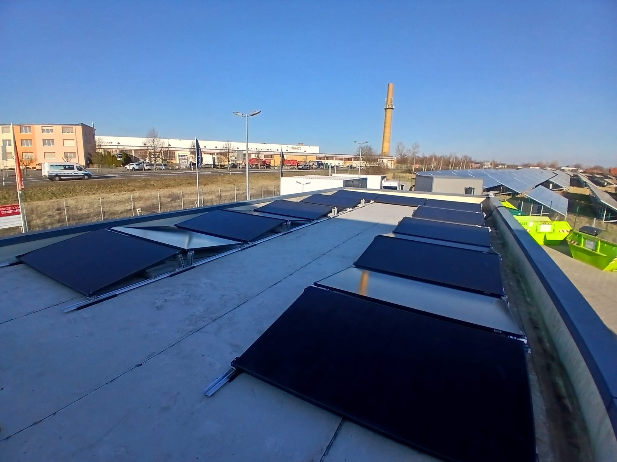 Solaranlagen auf einem Dach mit klarem Himmel und einem Schornstein im Hintergrund